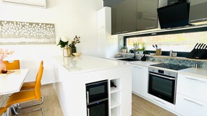 A modern kitchen with white cabinetry, a built-in oven, and a window with a view of greenery. - Mala Oaza in Sveti Petar u umi (Sveti Petar u Sumi)