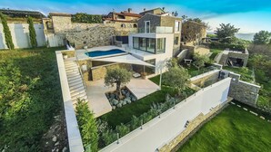 Une maison moderne dotée d’une piscine, de murs en pierre et d’un jardin bien entretenu.