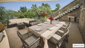 Un espace extérieur aménagé pour les repas, avec un mur en pierre et un escalier.