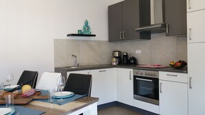 Une cuisine de taille réduite équipée d’une cuisinière, d’un four et d’une machine à café.