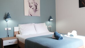 Une chambre à coucher avec un lit, des tables de chevet, une lampe fixée au mur et une affiche.