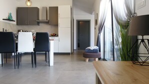 Une cuisine moderne avec des meubles de couleur sombre, un coin repas avec des chaises noires et une table en bois.