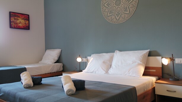 Une chambre avec deux lits, une table de chevet avec une lampe, un tableau décoratif au mur et une couvre-lit.