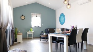 Un coin repas comprenant une table, des chaises, une horloge et une fenêtre avec des rideaux.