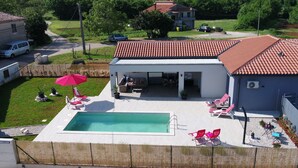 Une propriété résidentielle dotée d’une piscine, d’un espace extérieur aménagé et d’un patio couvert.
