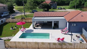 Ein Wohnhaus mit Pool, Außenbereich mit Sitzgelegenheiten und überdachter Terrasse.