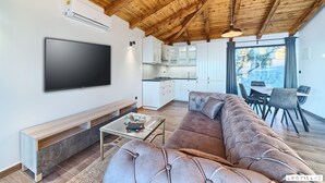 A modern living room with a large flat-screen TV, a sofa, a coffee table, and a wooden ceiling. - Lux IV in Murter With 2 Bedrooms and 1 Bathrooms (Tisno)