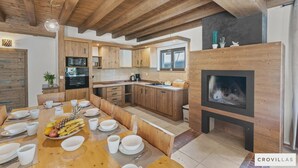 A modern kitchen with wooden cabinets, a dining area with a fruit bowl, and a fireplace. - Dali in Svetvin Enat (Svetvincenat)