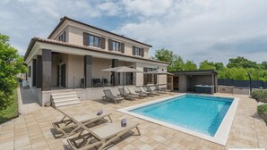 Eine moderne Villa mit Swimmingpool, Außenmöbeln und einer überdachten Terrasse.