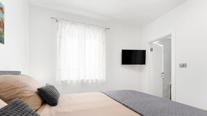 A bedroom with a bed, a television mounted on the wall, and a door leading to another room. - Grande Brscici in Svetvincenat (Svetvincenat)