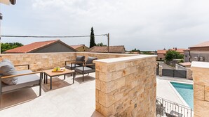 A rooftop patio with stone walls, a pool, and a view of neighboring buildings. - Grande Brscici in Svetvincenat (Svetvincenat)