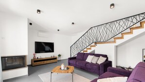 A modern living room with a staircase, a flat-screen TV, and a wooden coffee table. - Grande Brscici in Svetvincenat (Svetvincenat)