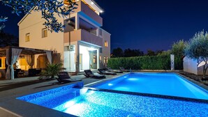 A modern two-story building with a swimming pool, outdoor seating, and a well-lit entrance. - Luce in Zadar With 4 Bedrooms and 4 Bathrooms (Benkovac)