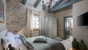 A bedroom with a stone wall, a bed with pillows, a wardrobe, a radiator, and a television. - Nevia in Ladi i With 5 Bedrooms and 5 Bathrooms (Kanfanar)
