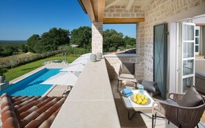 Ein Balkon mit Pool, Gartenmöbeln und einem Tisch mit Früchten.