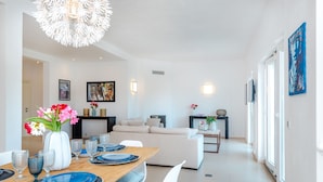 Una sala de estar moderna con comedor, que incluye una mesa de madera para cuatro, un sofá y una lámpara decorativa.