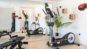 Un gimnasio en casa con equipo de ejercicio, un espejo y una planta en maceta.