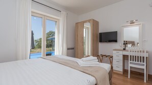 A bedroom with a bed, a desk, a chair, a television, and a view of the outdoors. - Laura An in Dekli i (Kastelir-Labinci)
