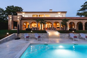 Uma casa grande com piscina, área de estar externa e entrada bem iluminada.