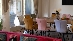 Een eetruimte met een houten tafel, meerdere stoelen en een vaas met bloemen.