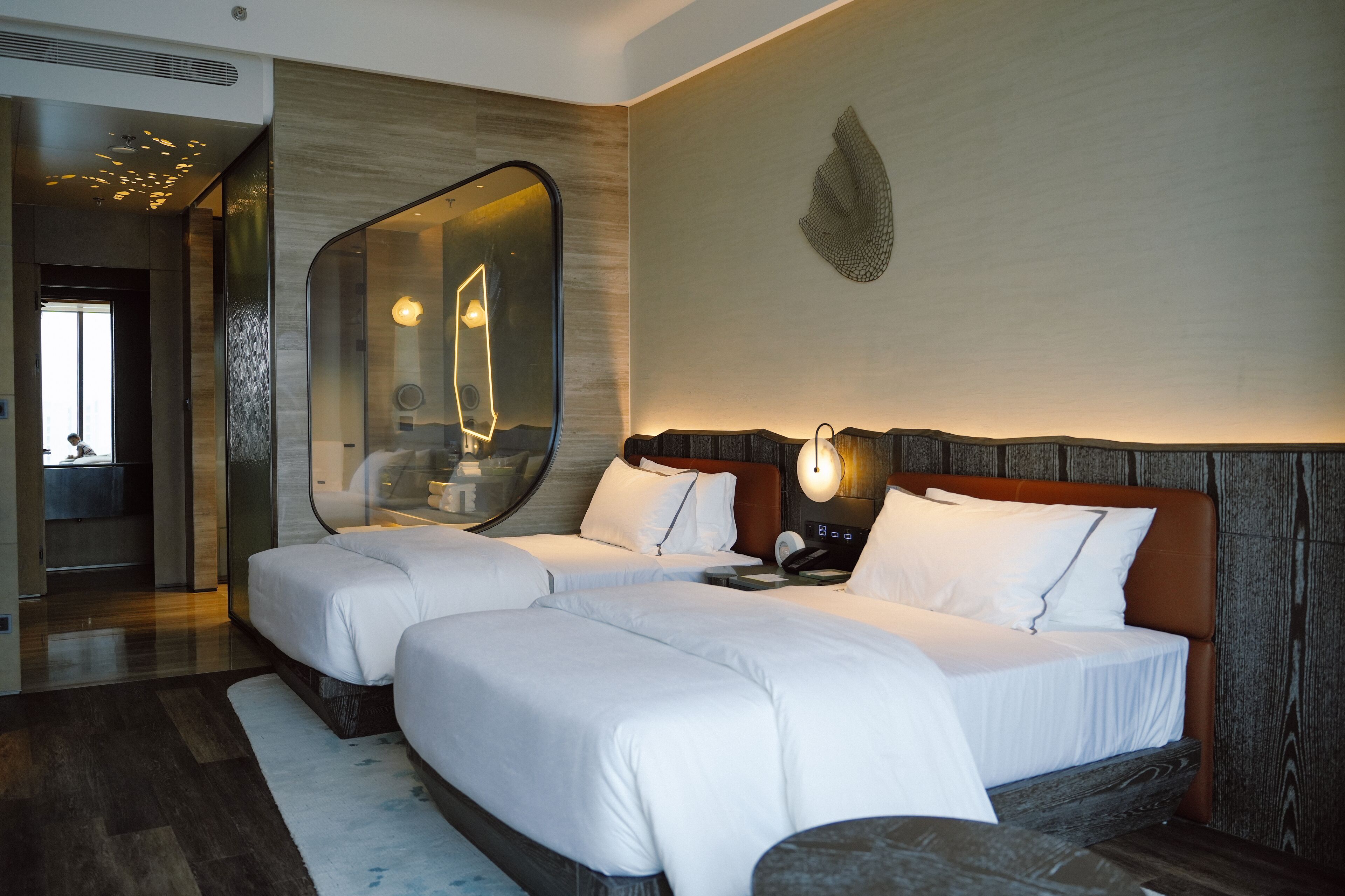 A hotel room with two beds, a large mirror, and a modern design.