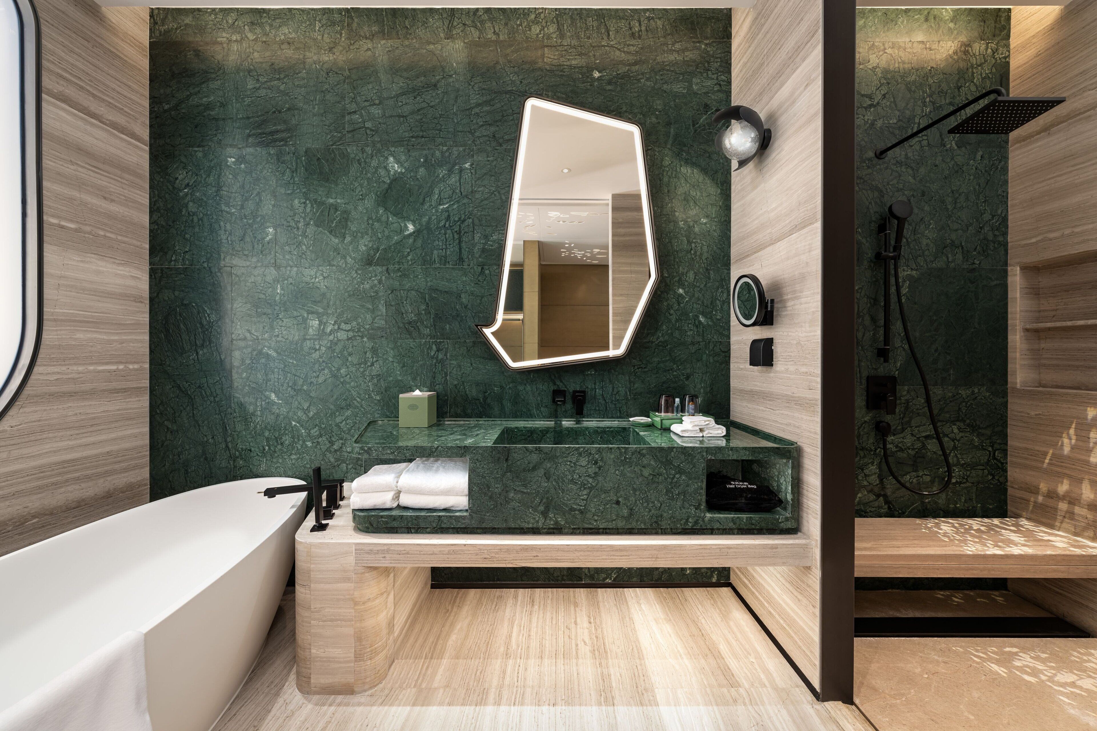 A modern bathroom with a large mirror, a bathtub, and a shower area.