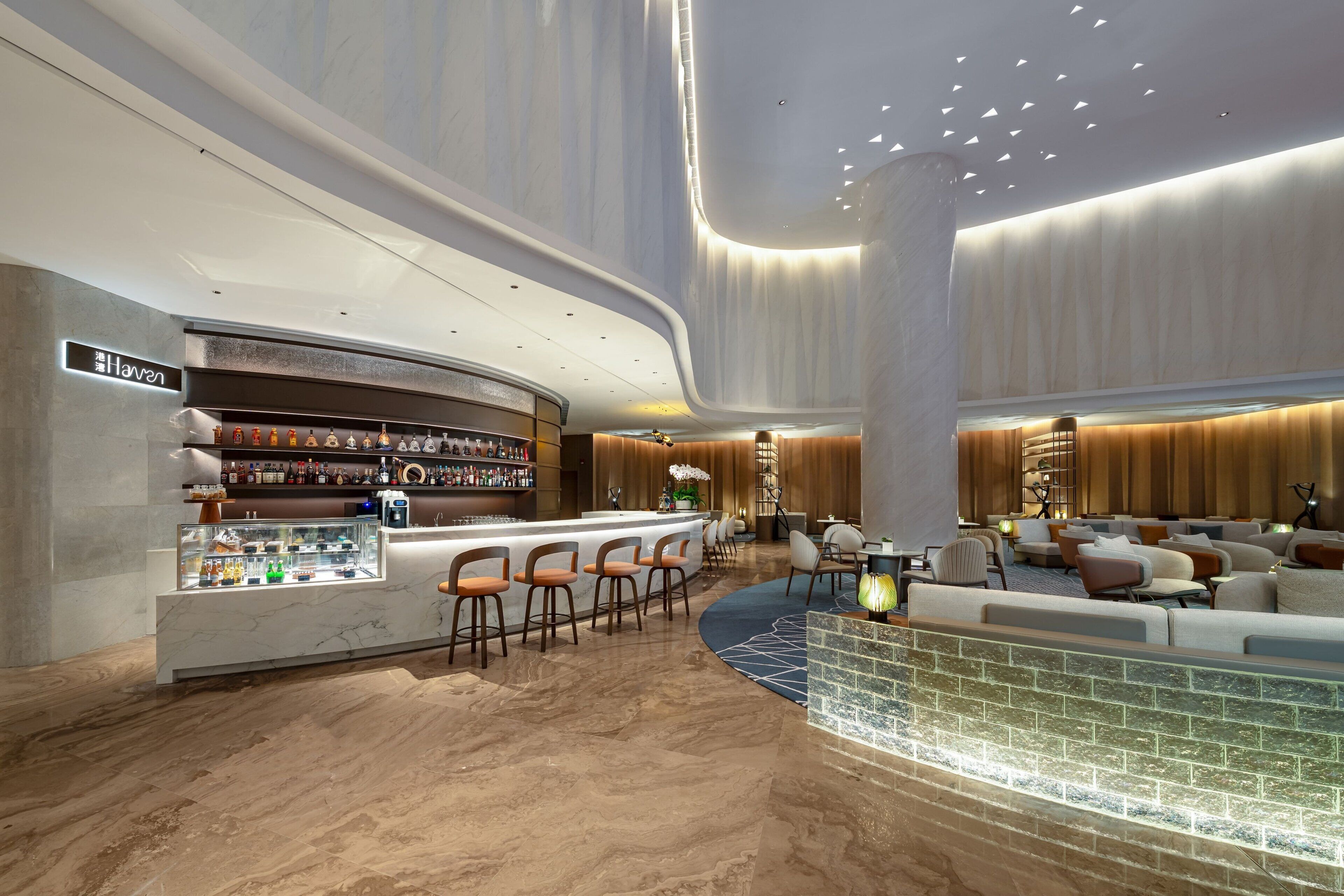 Un lobby moderno con zona de bar, asientos y una fuente decorativa.
