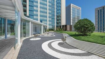 Un edificio moderno con amplios ventanales y un camino ajardinado con diseños circulares.