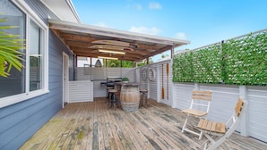 Eine Außenpatio mit Holzdeck, Grill und Sitzgruppe mit Holzstuhl.