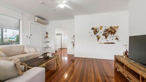 Een moderne woonkamer met een houten vloer, een bank, een salontafel en een tv-meubel.