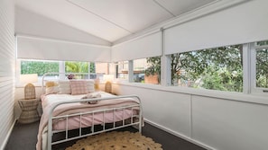 Een slaapkamer met een bed, een raam en uitzicht op groen.