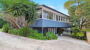 A modern two-story house with a flat roof, large windows, and a covered patio area.