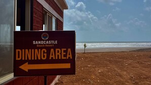 Skilt for Sandcastle Beach Resort spiseområde med udsigt over stranden og havet.