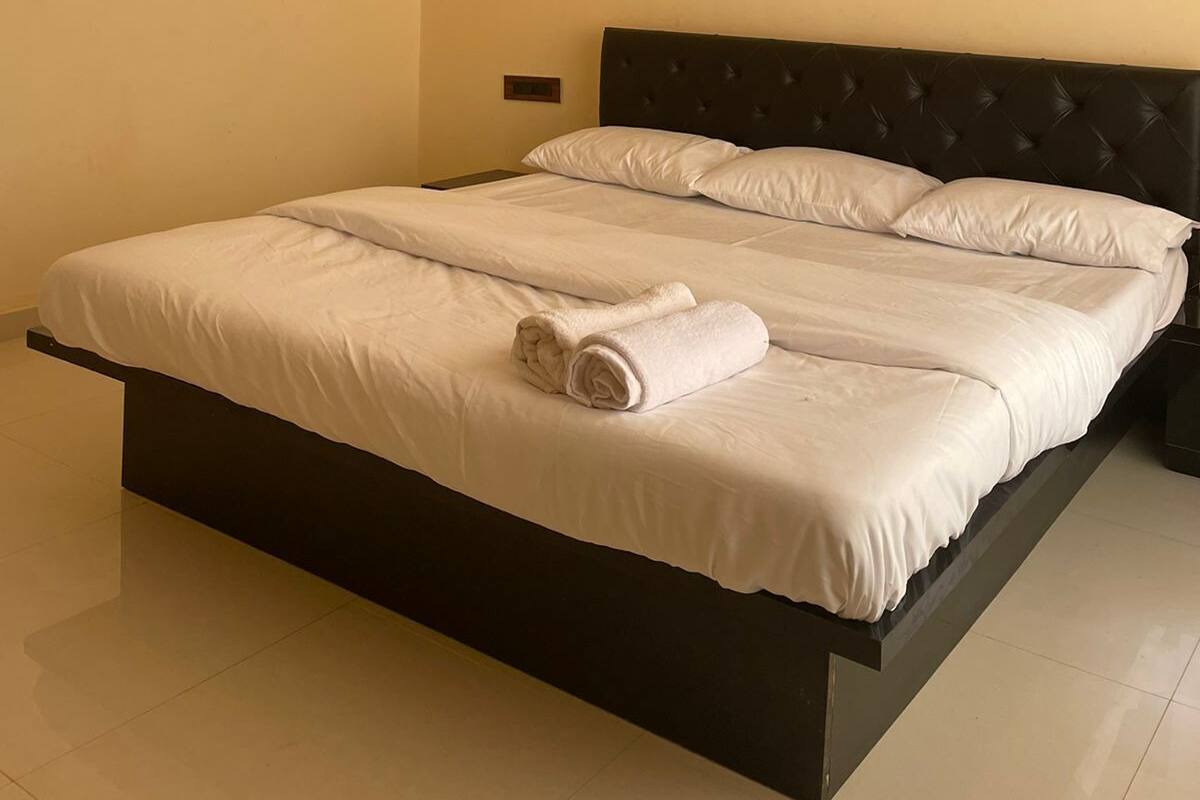 A neatly made bed with white linens and rolled towels, a dark headboard, and a ceiling fan.