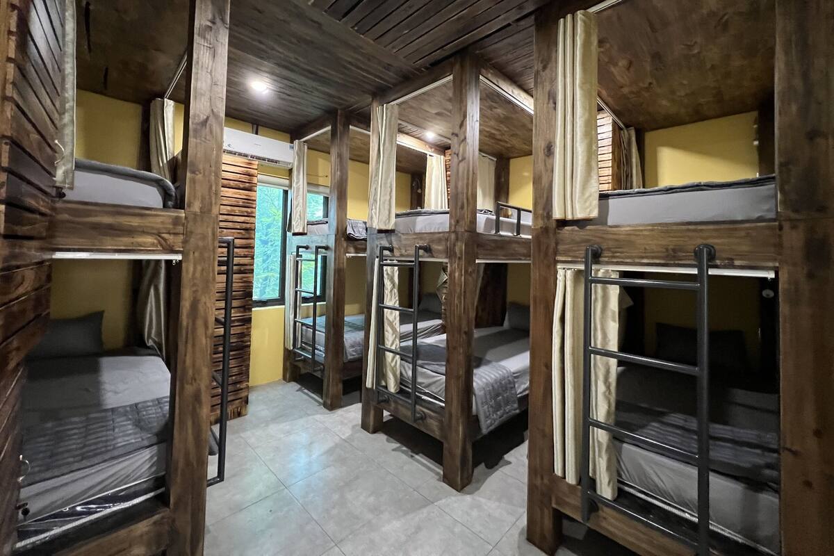 A dormitory room with bunk beds, wooden walls, and a tiled floor.