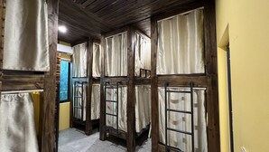 A corridor with bunk beds, wooden beams, and curtains. - Lapis Restaurant and Hostel (Nam Hoa Lu)