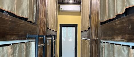 A narrow hallway with wooden walls and a tiled floor, leading to a door with a frosted glass panel.