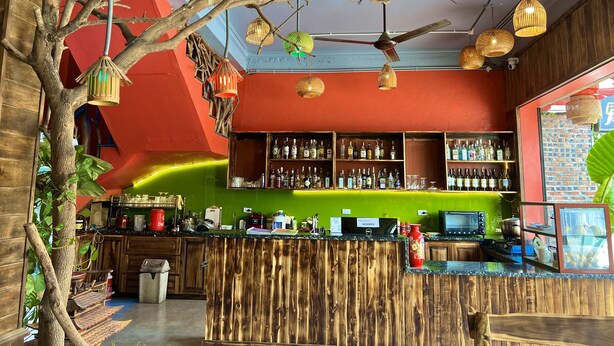A bar with wooden bar counters, shelves of liquor bottles, and hanging decorative lights. - Lapis Restaurant and Hostel (Nam Hoa Lu)