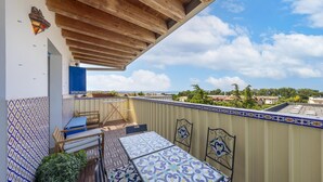 Un balcon doté d’un plafond en bois, de carreaux décoratifs et offrant une vue sur le paysage urbain.