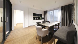 Ein moderner Essbereich mit einem großen Tisch, zwei grauen Sofas und einer Küche im Hintergrund.