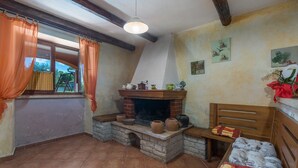 A rustic room with a fireplace, a wooden bed, and a window with curtains. - Prisedi in Rakalj With 4 Bedrooms and 3 Bathrooms (Marcana)
