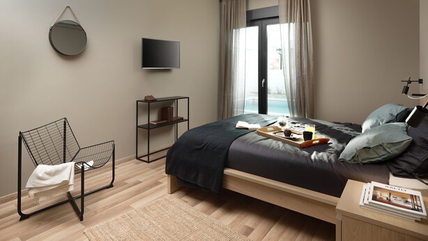 A modern bedroom with a bed, a TV, a chair, a shelf, and a window with curtains. - Median in Vodnjan With 4 Bedrooms and 2 Bathrooms (Vodnjan)