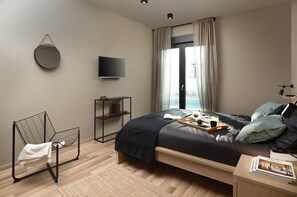A modern bedroom with a bed, a TV, a chair, a shelf, and a window with curtains. - Median in Vodnjan With 4 Bedrooms and 2 Bathrooms (Vodnjan)
