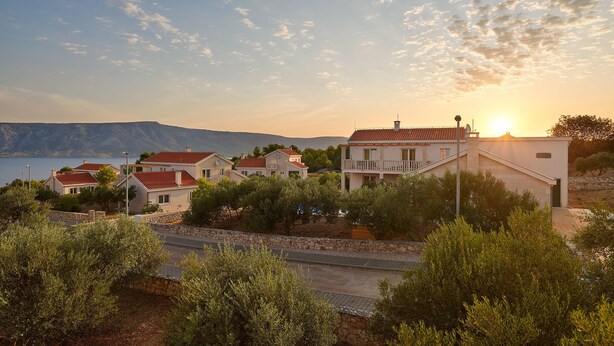 A coastal village with houses, a road, and a body of water in the background. - Doris Hvar in Rudina Hvar (Stari Grad)
