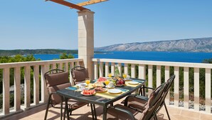 A terrace with a table set for breakfast, overlooking a scenic view of the sea and mountains. - Doris Hvar in Rudina Hvar (Stari Grad)