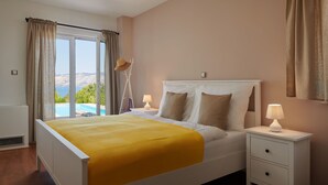 A bedroom with a bed, a nightstand, a lamp, and a view of the sea. - Doris Hvar in Rudina Hvar (Stari Grad)