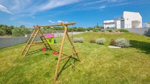A wooden swing set in a grassy backyard with a modern house in the background. - Elsa in Krnica With 4 Bedrooms and 4 Bathrooms (Marcana)