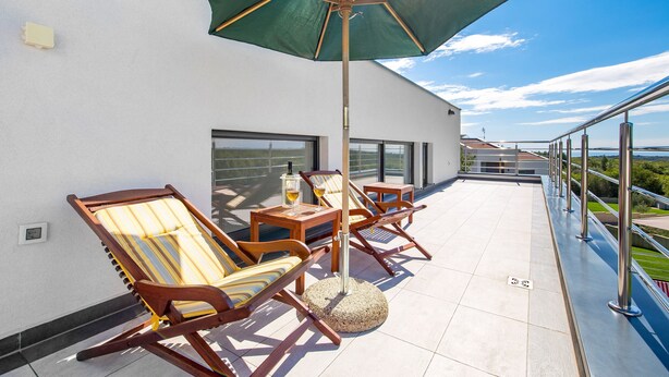 A rooftop terrace with wooden lounge chairs, a table, and a green umbrella. - Elsa in Krnica With 4 Bedrooms and 4 Bathrooms (Marcana)