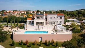 Una amplia villa moderna con piscina, varios balcones y un jardín bien cuidado.