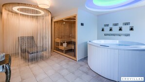 Moderni spa-huone, jossa on puinen sauna, hierontatuoli ja poreallas.